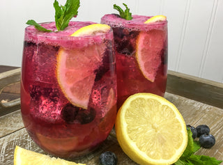blueberry maple lemonade in a stemless wine glass with lemon garnish