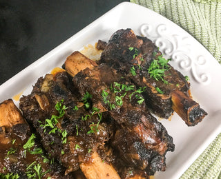 perfectly cooked beef back ribs fresh out of the slow cooker and on a white dinner plate 