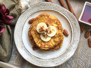 Delicious pumpkin spice pancakes with banana and pecans on a white dinner plate Pumpkin spice pancakes recipe image 