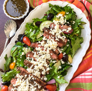 Farm Fresh Greek Steak Salad  with fresh greens and bright colors on a white plate 