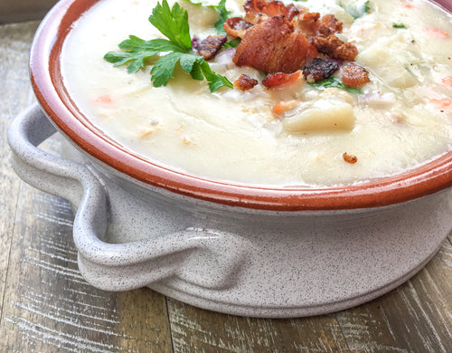 Delicious new england clam chowder in a stoneware bowl and garnished 