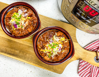 Instant pot pulled pork chili in clay bowls on a wooden cutting board