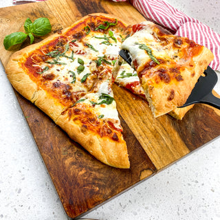 colorful deep dish margherita pizza on a board with server 