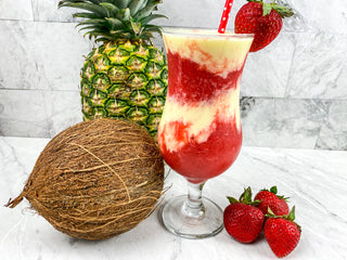 Frozen blended miami vice drink in a cocktail glass with a coconnut and pineapple in the background recipe image 