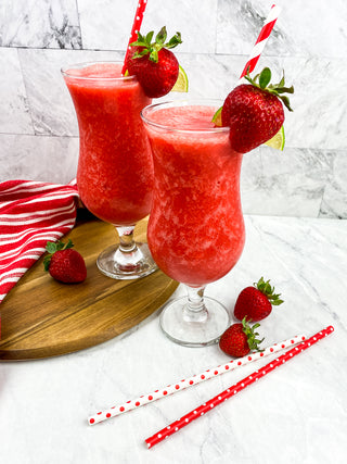 freshly blended strawberry daiquiri in hurrican glass with strawberries and cutting board Recipe image 