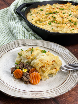 delicious cast iron Shepherd's pie recipe image with colorful vegetables on a plate with cast iron skillet fresh from the oven in the background